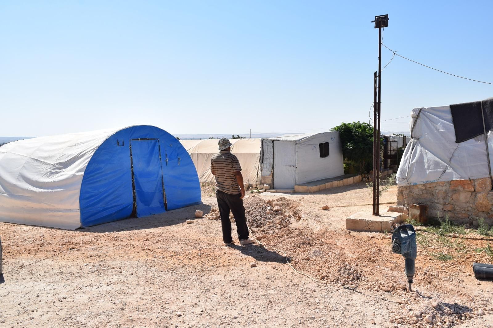 A man is standing in front of a blue tent.