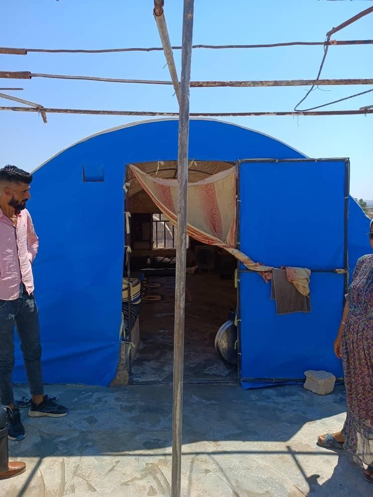 Ein Mann und eine Frau stehen vor einem blauen Zelt.