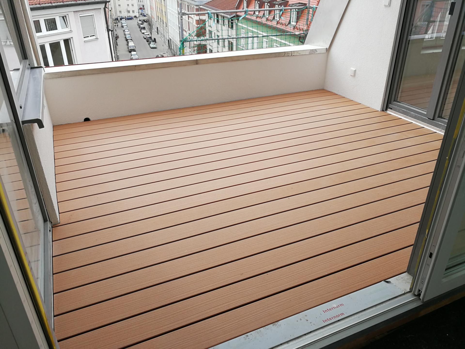 Balkon mit gelochten, rutschfesten Terrassenplatten in hellem Holzdesign.