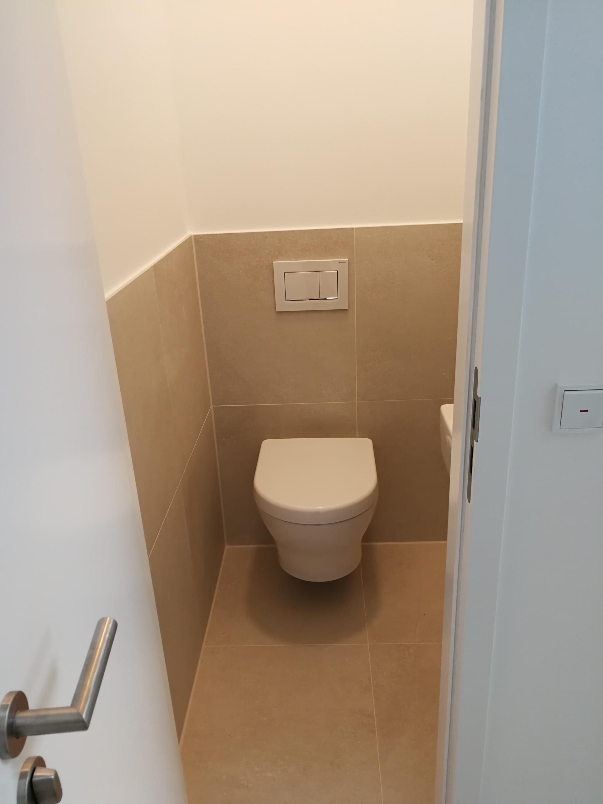 Kleines, modernes Bad mit wandhängendem WC und beigen Fliesen.