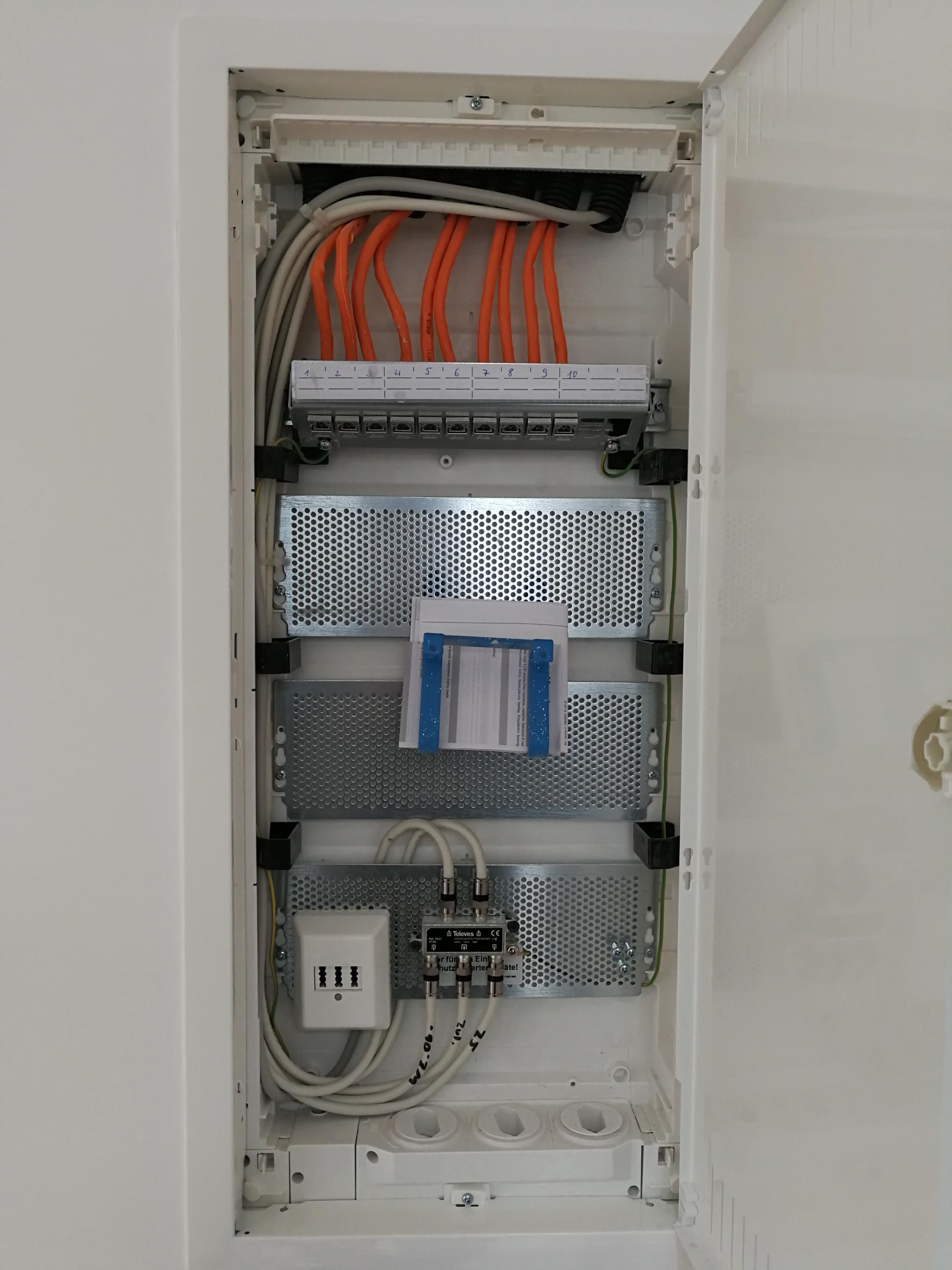 Geöffneter Sicherungskasten mit installierten Stromleitungen und Verteiler im Innenraum.