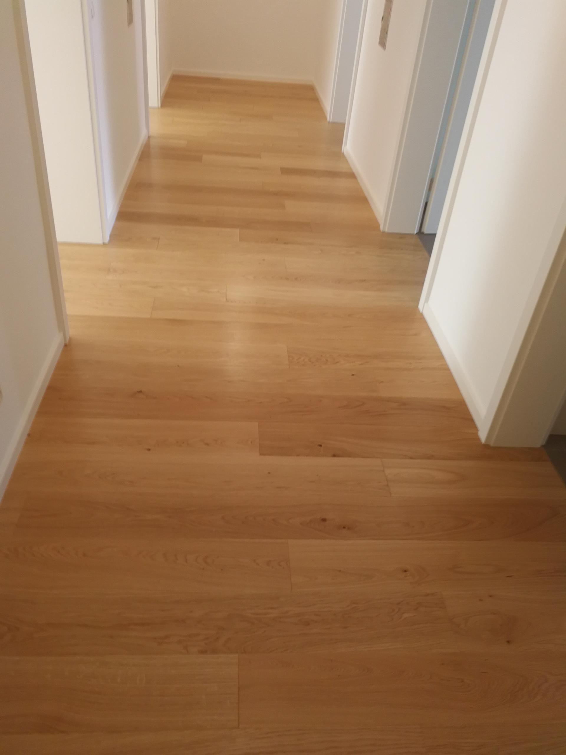 Übergang zwischen zwei Räumen mit hellem Laminatboden und weißen Wänden.