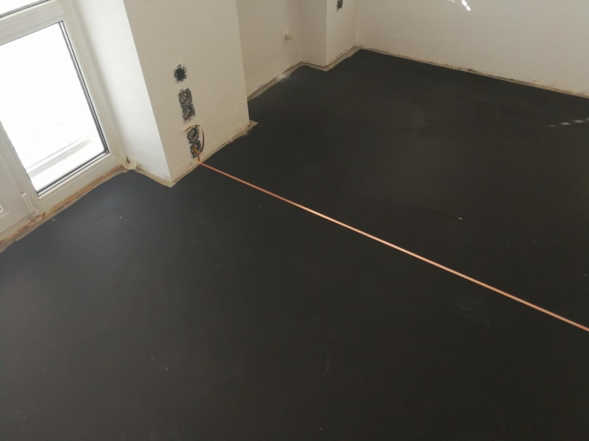 Schwarzer Boden mit Kupferband, vorbereitet für eine spezielle Bodenverlegung.