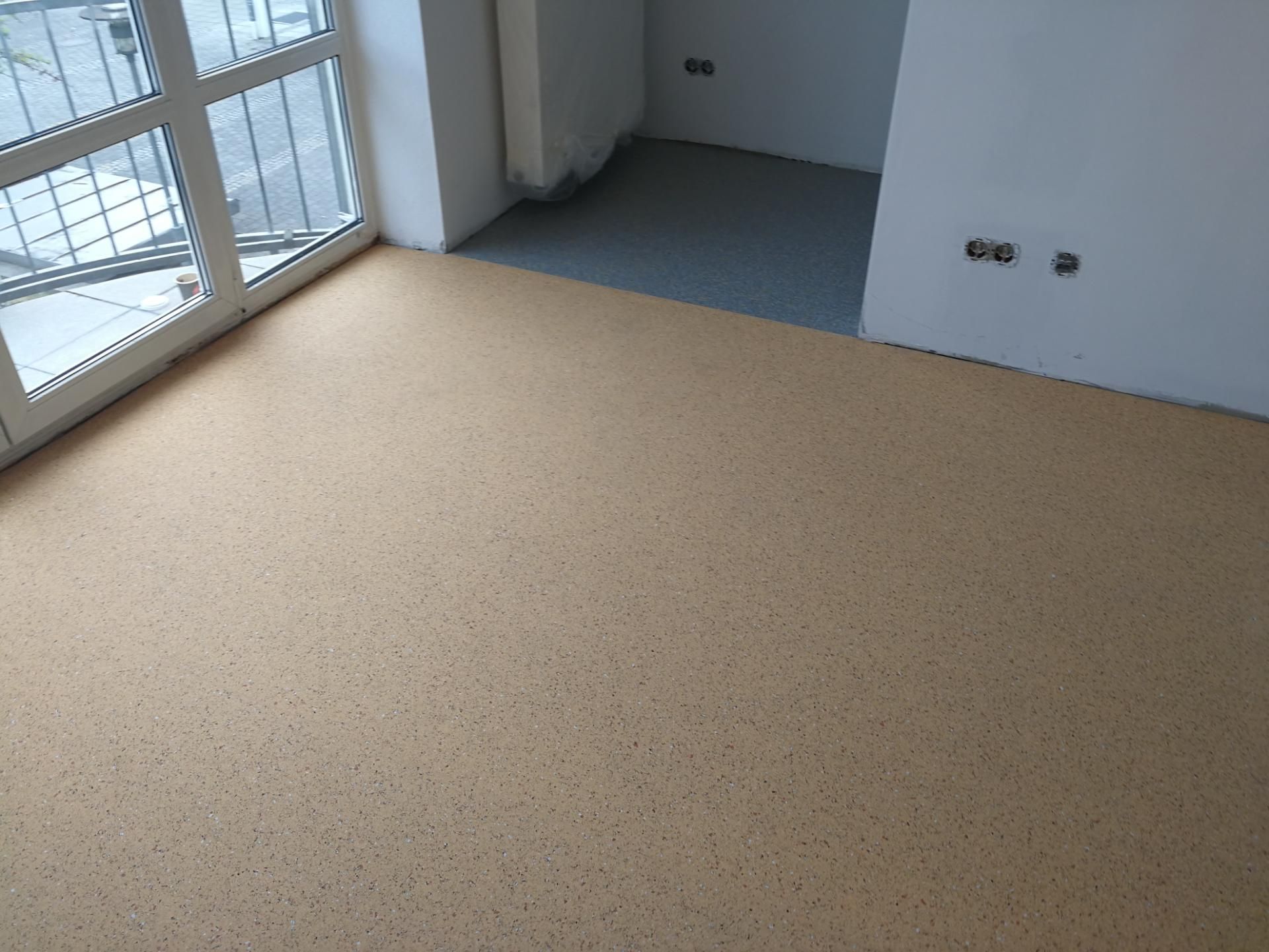 Raum mit neu verlegtem Korkboden und angrenzendem grauem Belag am Rand.