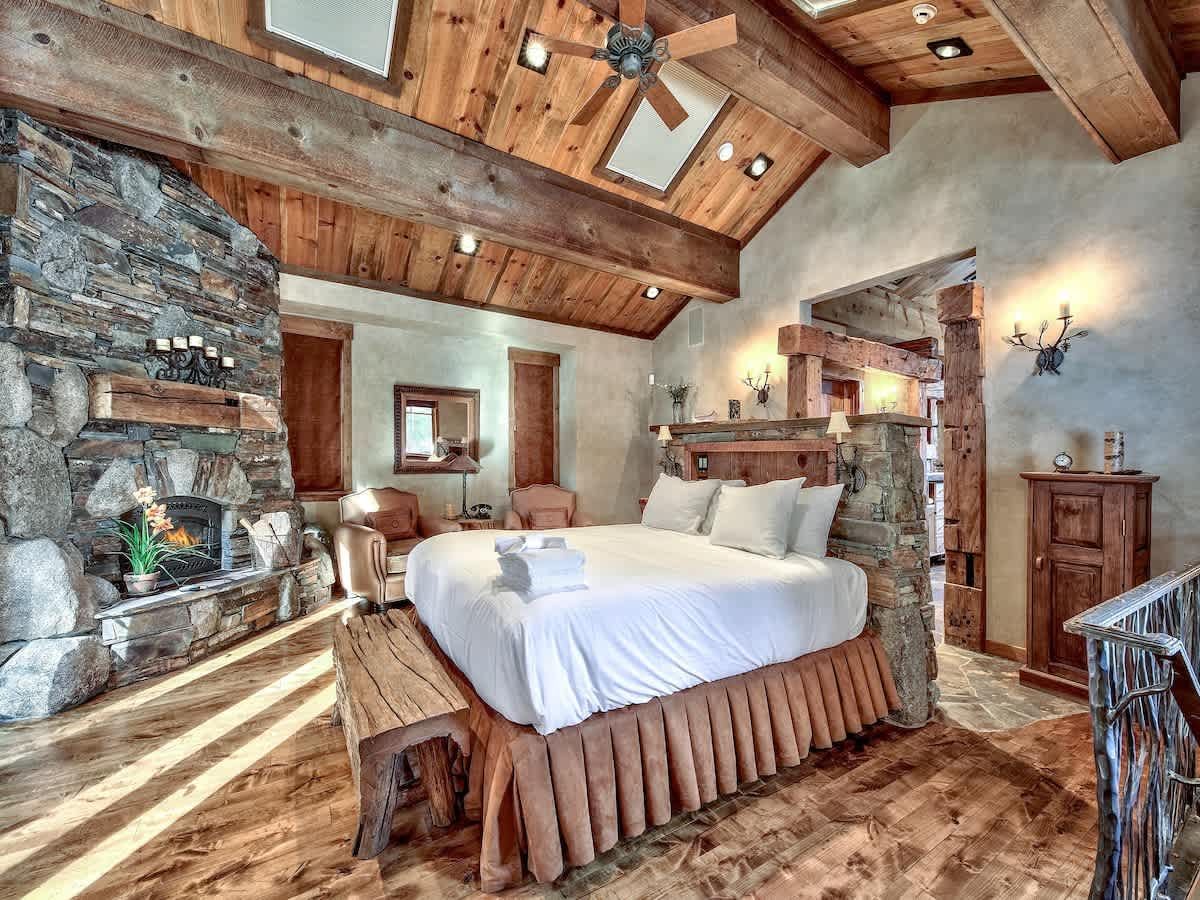 Bright bedroom with a large bed, ceiling fan, dresser, nightstand, and window blinds.