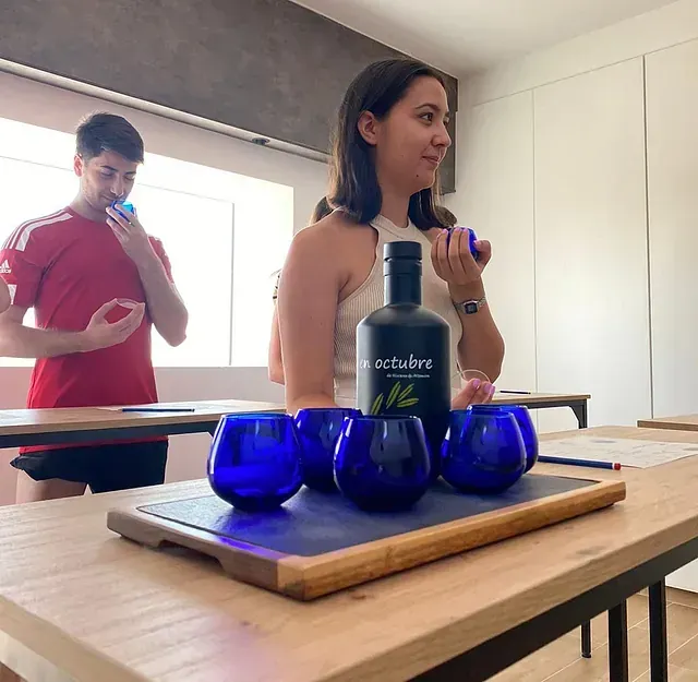 Una mujer sentada en una mesa con una botella de Octubre encima.