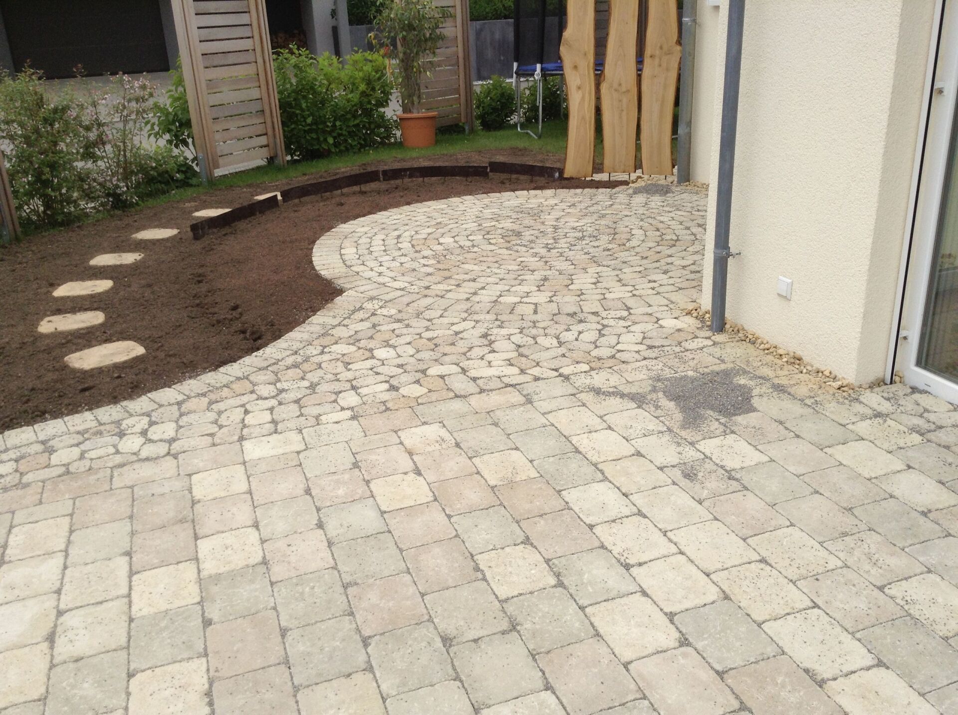 Eine Terrasse mit Ziegeln und Trittsteinen vor einem Haus