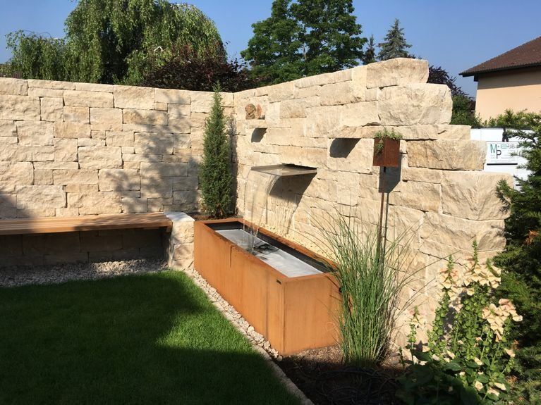 Ein Garten mit einer Backsteinmauer und einer Holzbank.