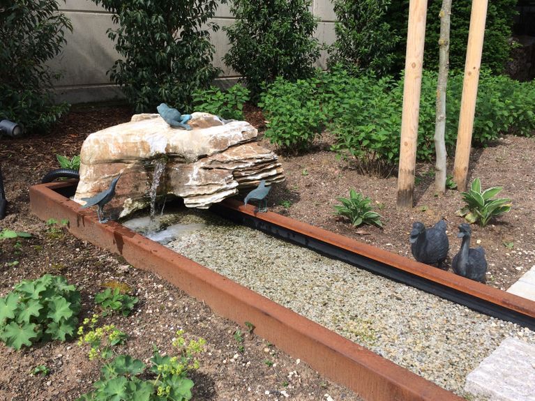 Mitten im Garten befindet sich ein Wasserfall.