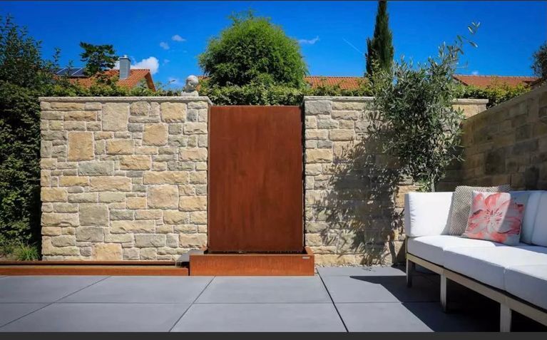 Eine Terrasse mit einer Couch und einer Steinmauer