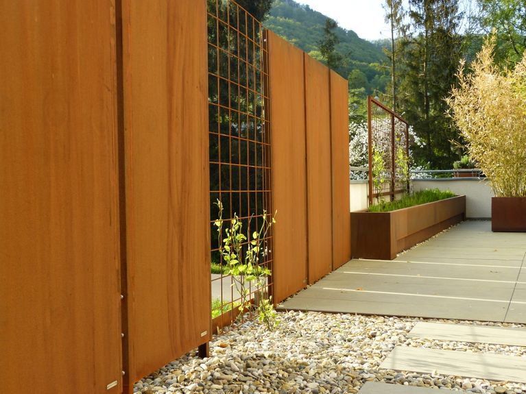 Ein rostiger Zaun mit einem Blumentopf im Hintergrund