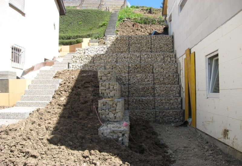 Vor einem Haus wird eine Steinmauer gebaut