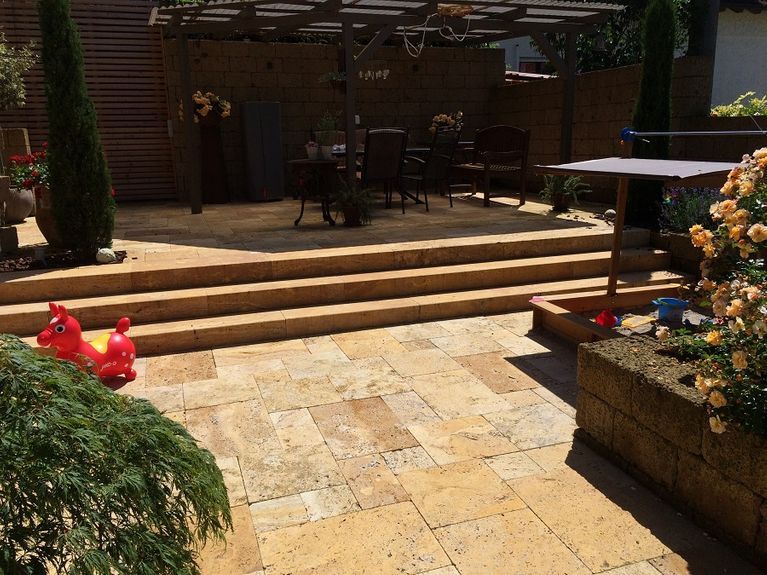 Eine Terrasse mit Stufen, die zu einem Tisch und Stühlen führen.