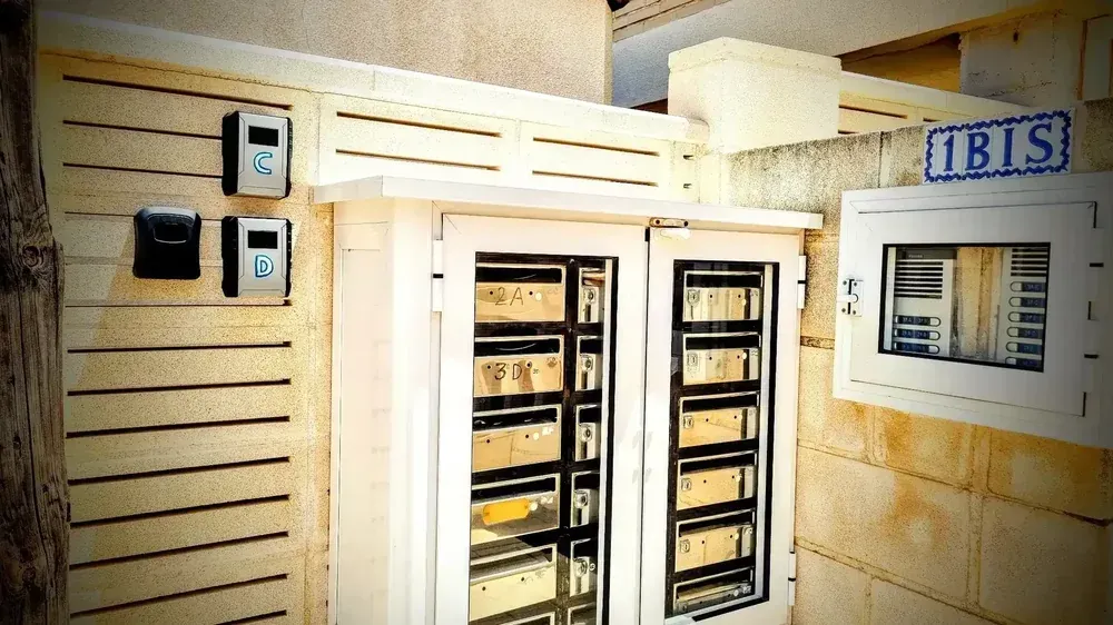 Puerta blanca con cristales y rejas metálicas, cuadros eléctricos y un cartel que dice "IBIS".