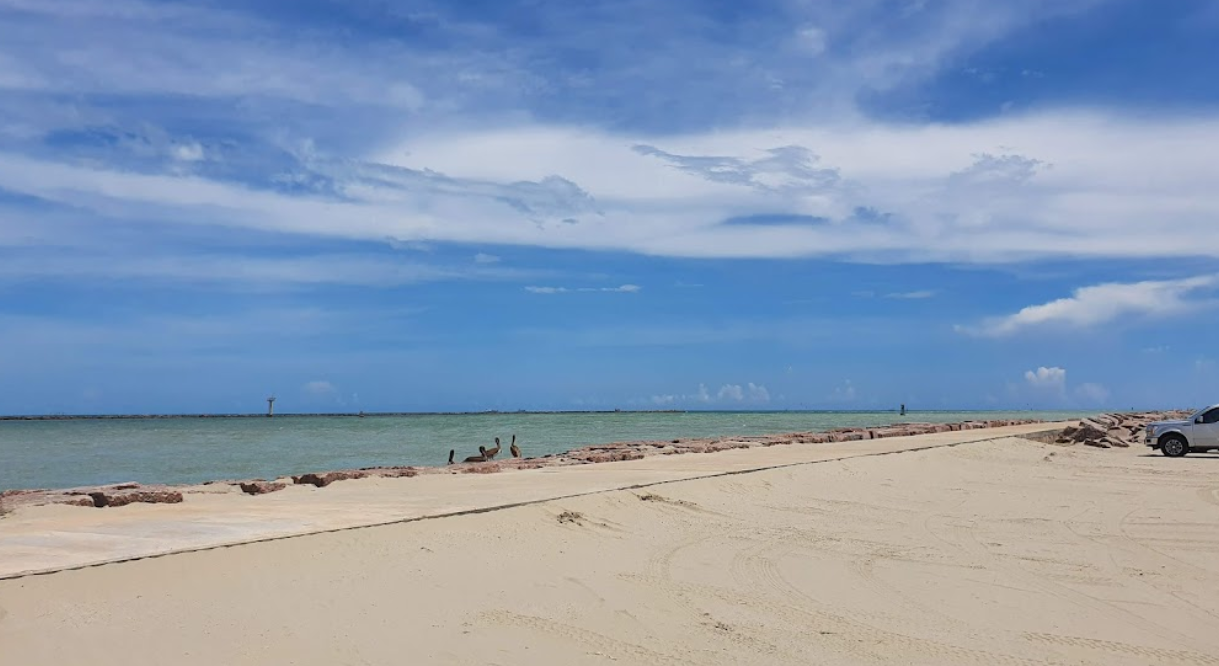 A car is parked on the beach next to I.B. Magee beach Park