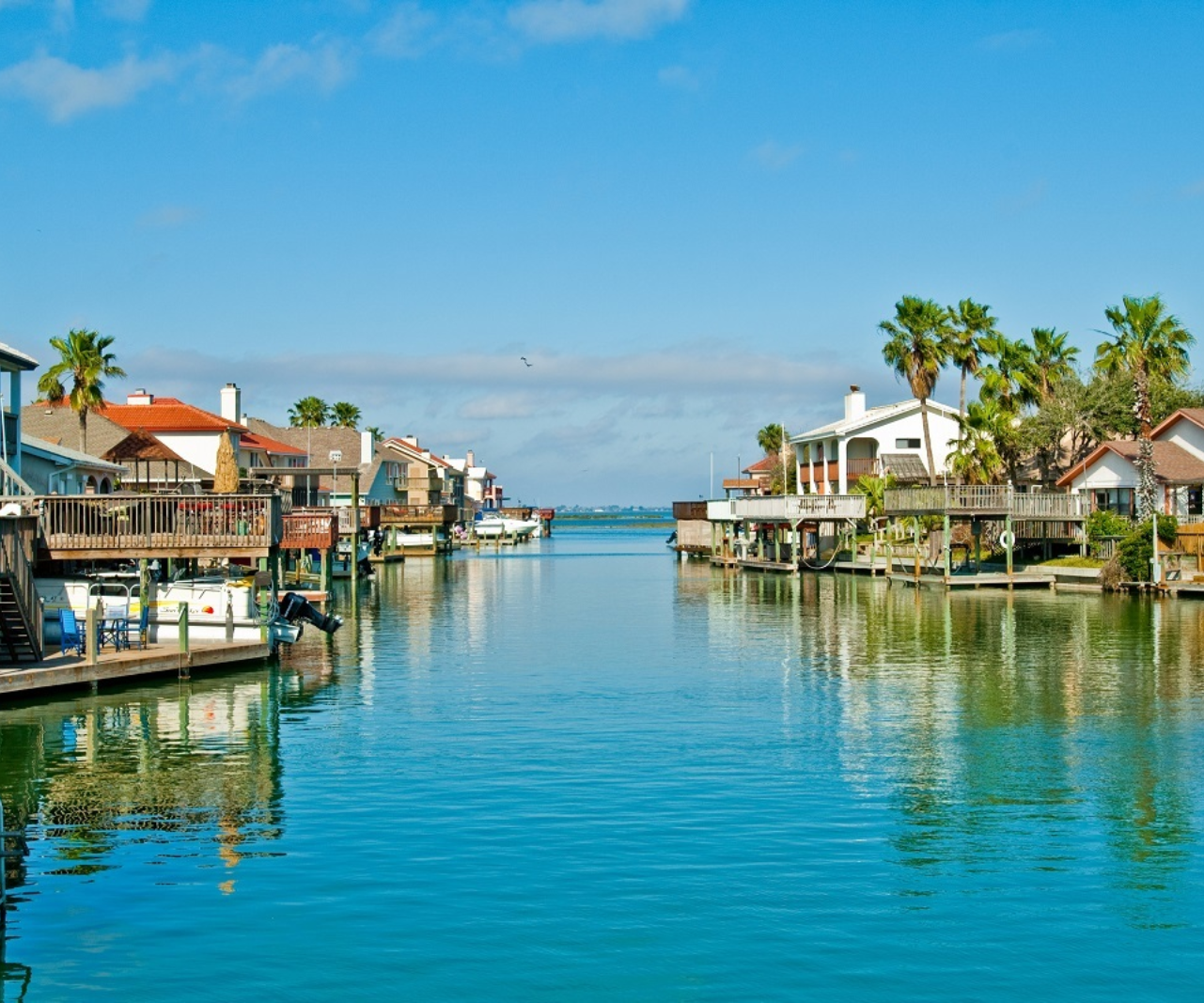 A row of houses sit on the shore of a body of water in North Padre Island, Texas