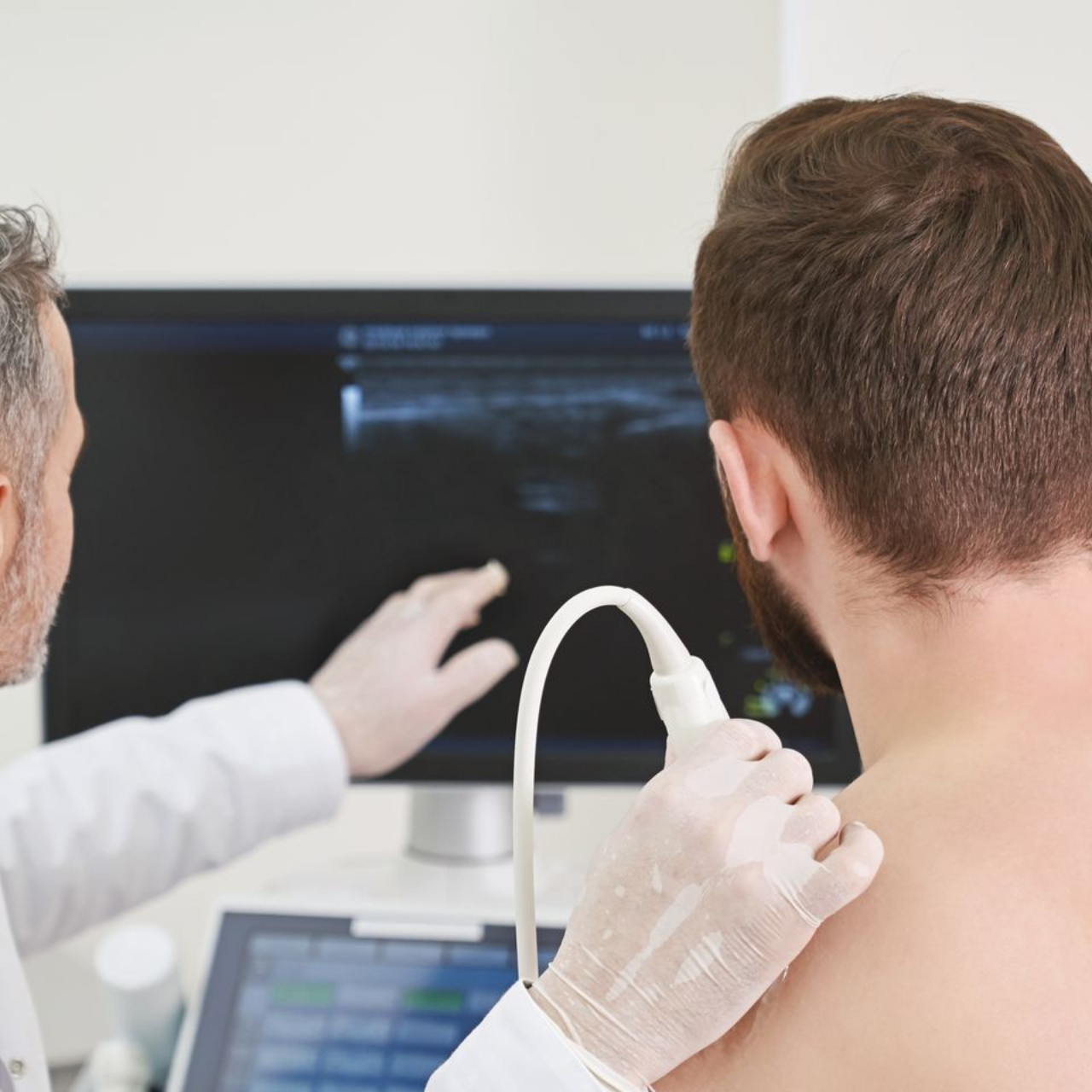 Patient et médecin assis devant l'écran d'une machine à ultrasons