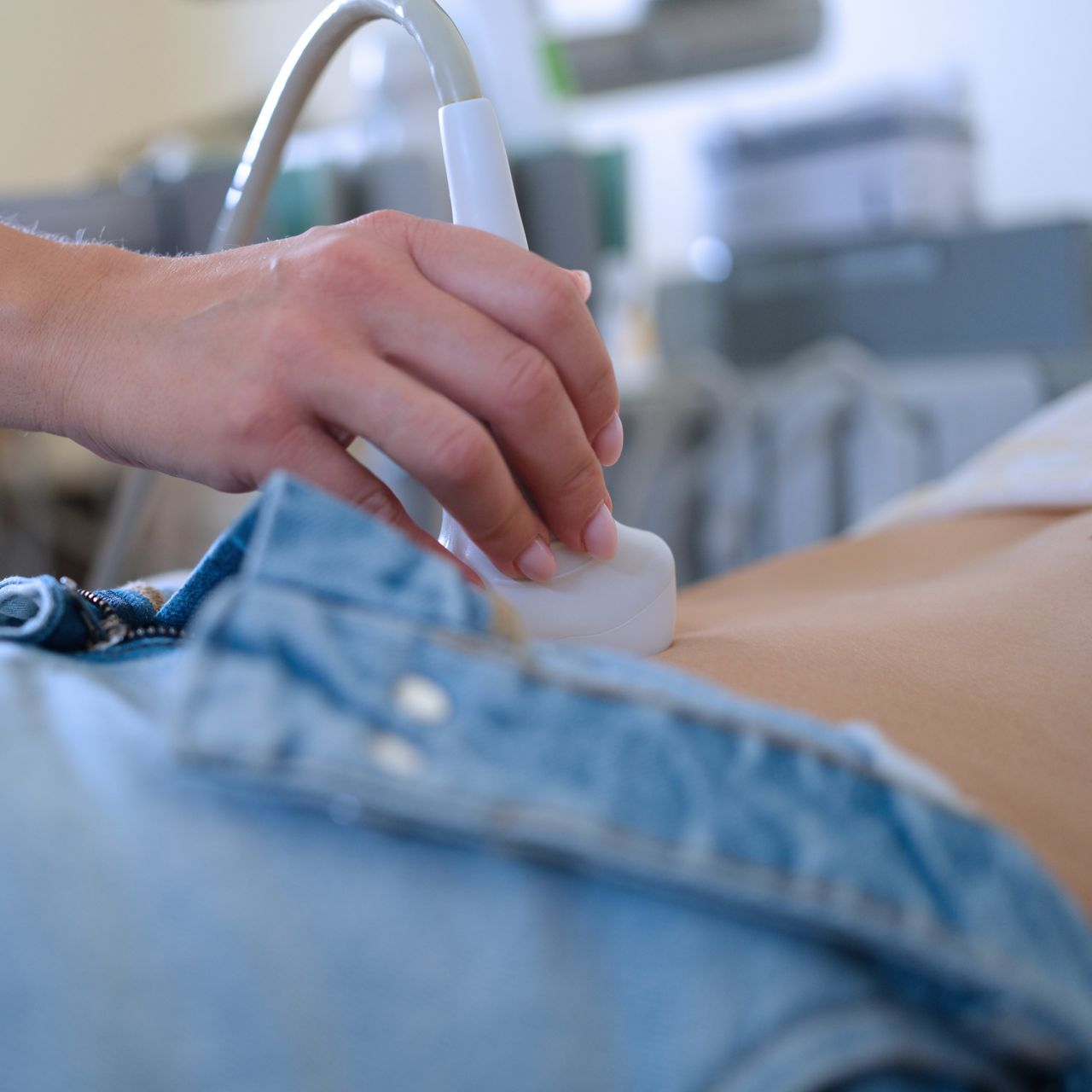 L'abdomen d'une personne est examiné à l'aide d'une sonde à ultrasons. On distingue un jean