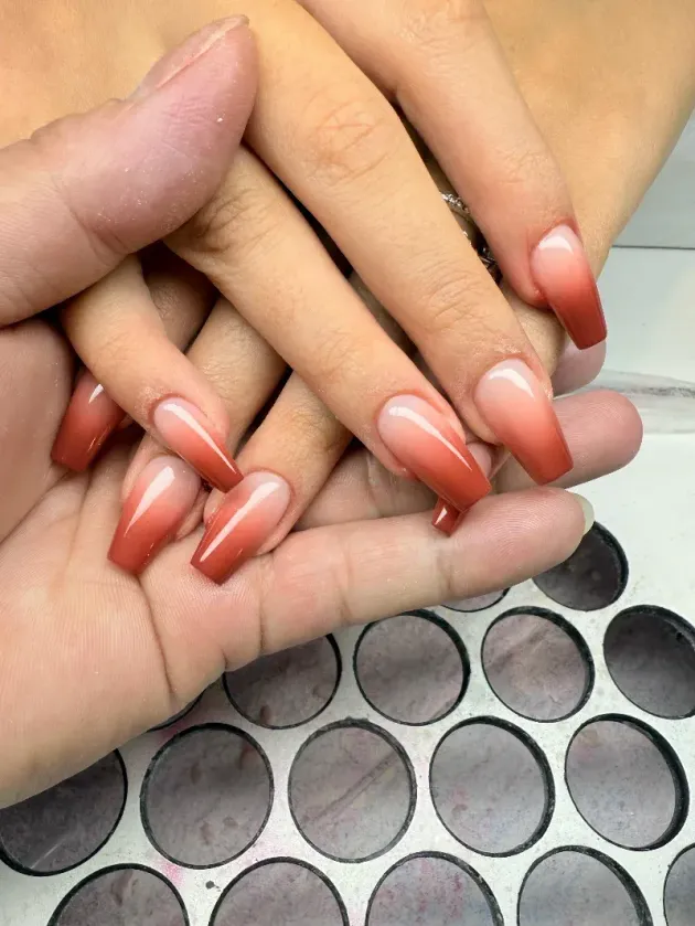 Hände mit langen schwarzen und pinkfarbenen Nägeln ruhen auf Chanel-Schachteln.