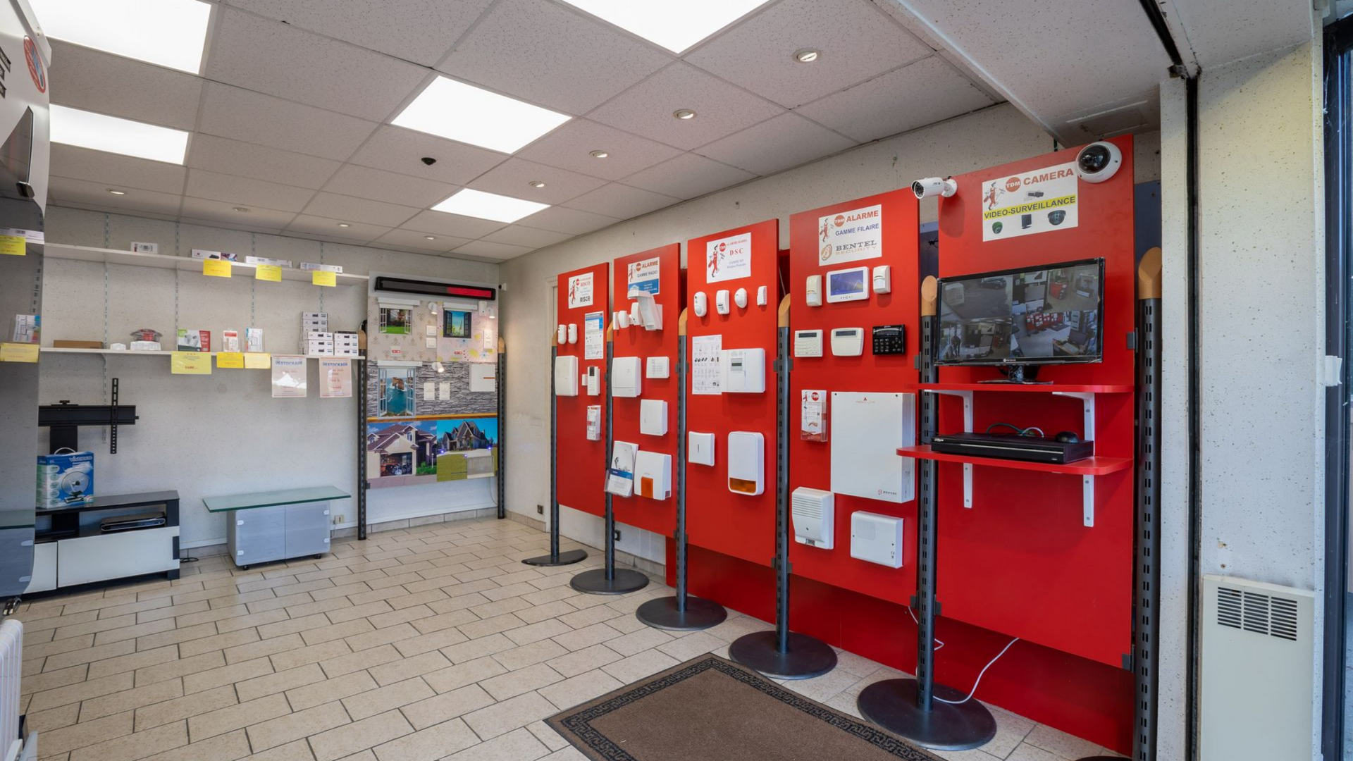 Intérieur d'un magasin présentant des appareils de sécurité sur des panneaux rouges.
