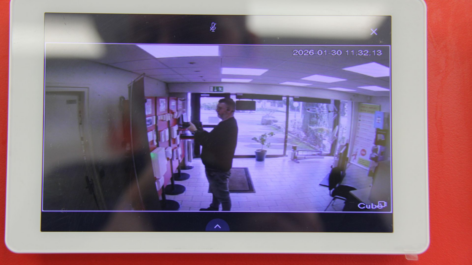 Présentation d'équipements de sécurité Bentel sur un mur rouge, comprenant un panneau de commande et des détecteurs de mouvement.