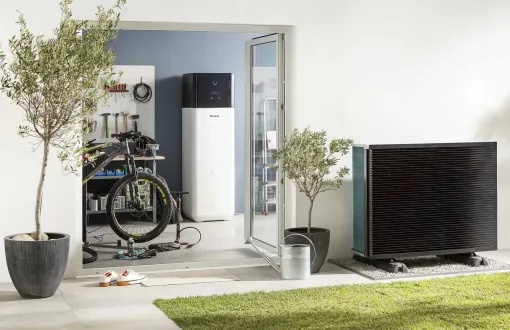 Patio moderne avec portes ouvertes, plantes en pot, vélo et grande télévision à côté d'une pelouse.