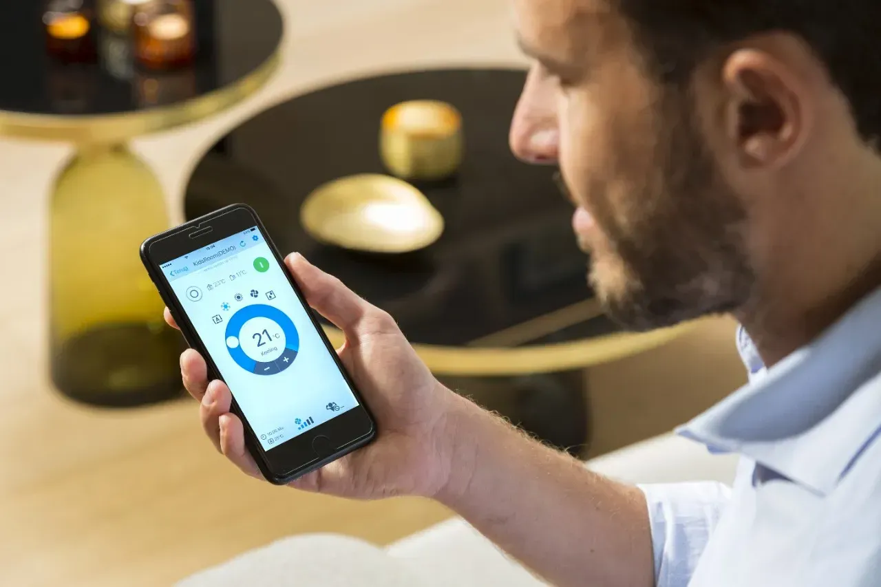 Un homme utilise une application pour smartphone dotée d'une interface circulaire bleue, assis à une table avec des bougies chauffe-plat.