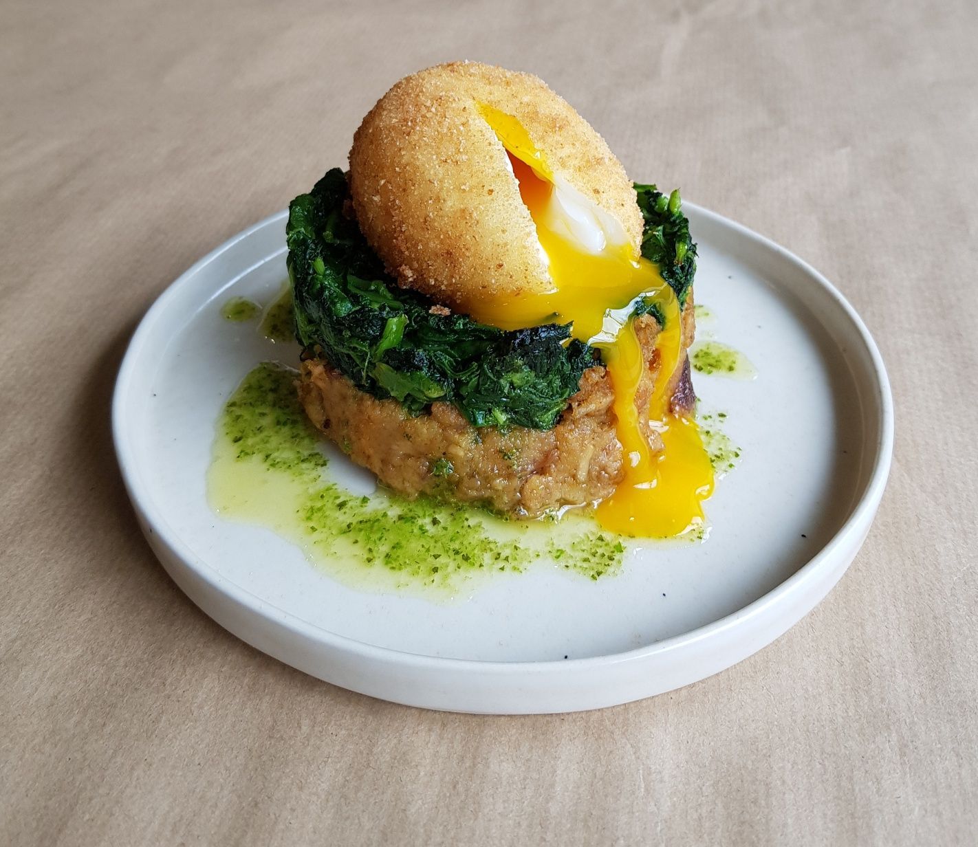 Um prato branco coberto com um ovo frito e espinafre