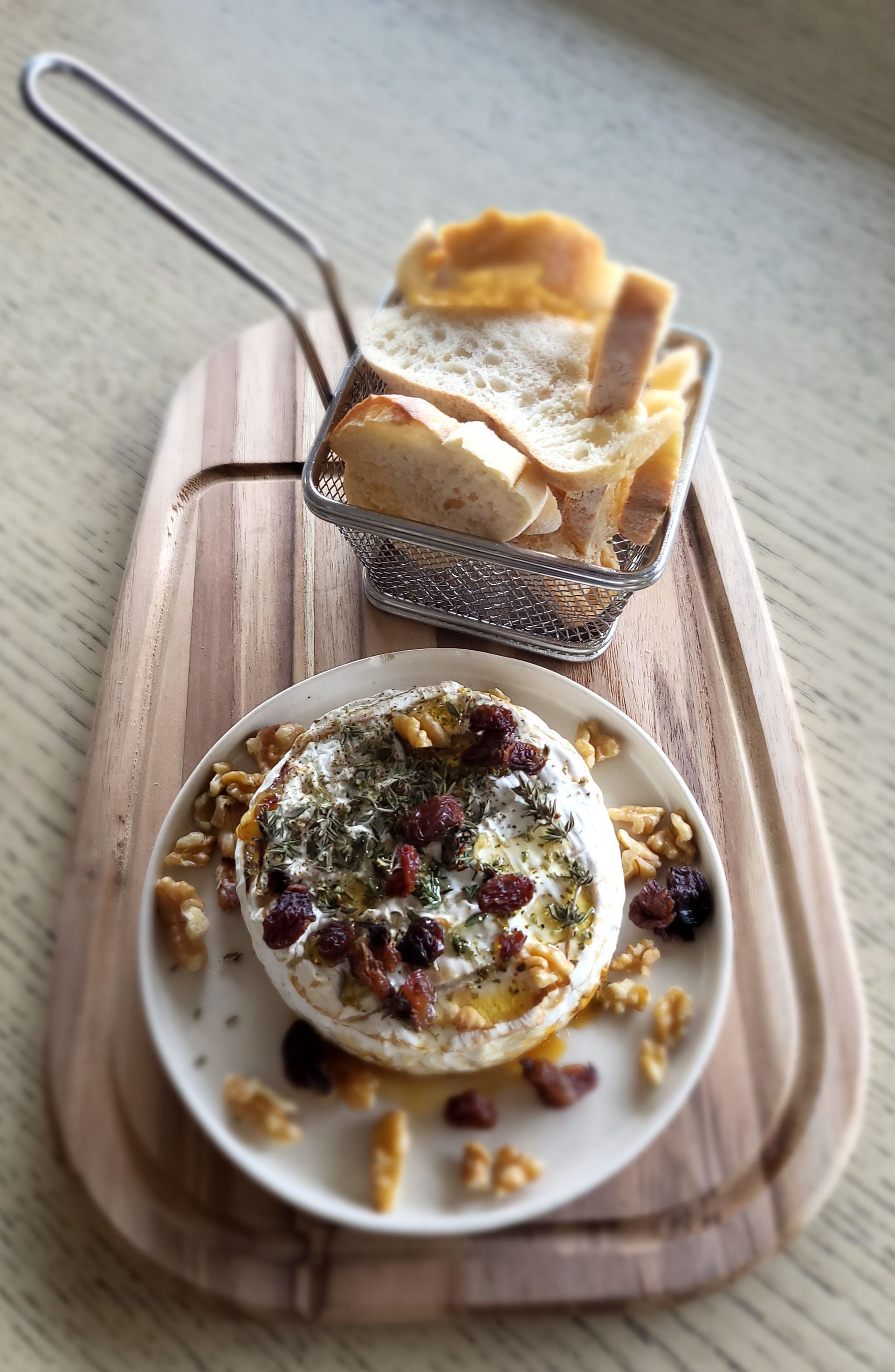 Um prato de comida em uma tábua de corte de madeira ao lado de uma cesta de pão