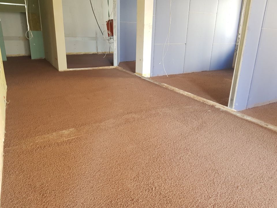 Brauner, strukturierter Boden in einem Raum mit blauen und beigen Wänden, Türen sind sichtbar.