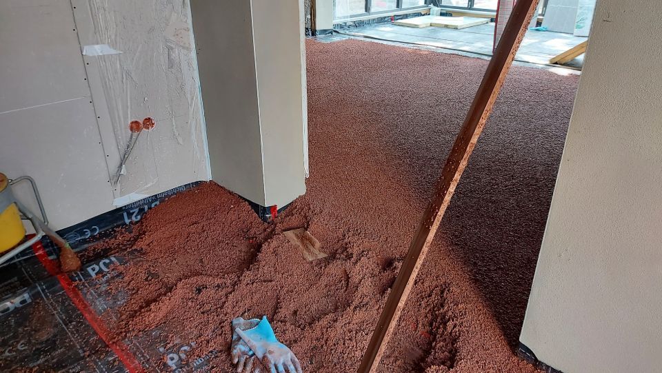 Innenausstattung: Raum mit rotem Kiesboden, der den Unterboden freilegt. Ein Holzbalken und ein Handschuh liegen auf dem Boden.