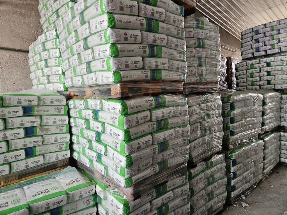 In einem Lagerhaus sind Paletten mit weißen und grünen Säcken eines Produkts beladen.