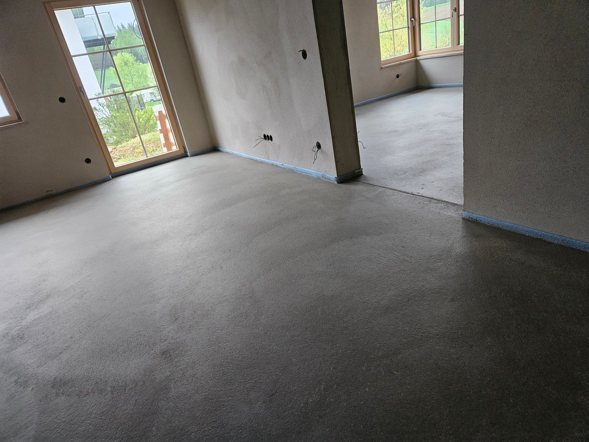 Installation einer Fußbodenheizungsanlage mit schwarzen Rohren auf weißem Untergrund; Person hält einen weißen Schlauch.