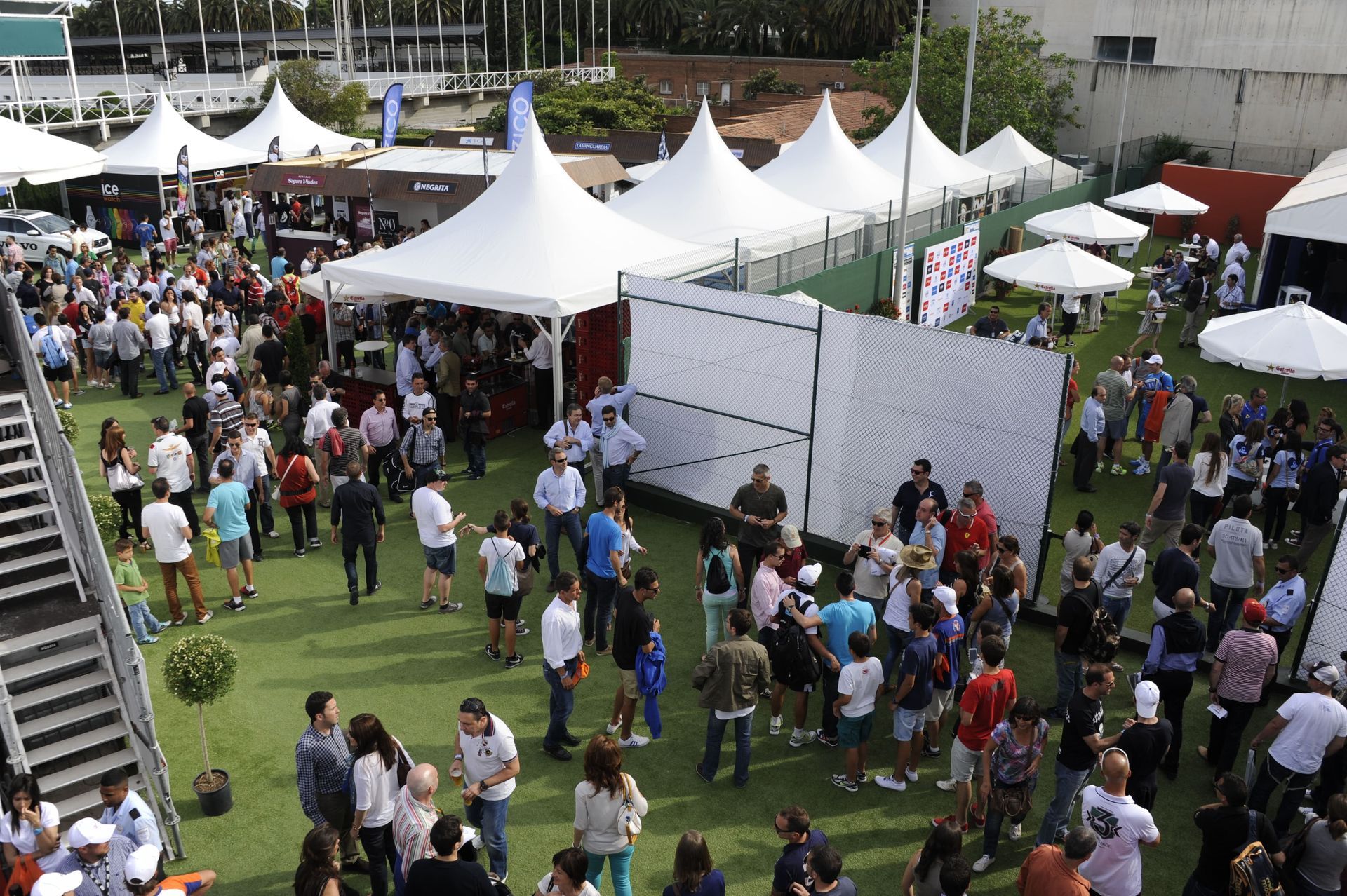 Gran evento al aire libre con mucha gente, carpas y un espacio verde.