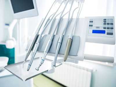 Una silla dental con un montón de instrumentos dentales encima.