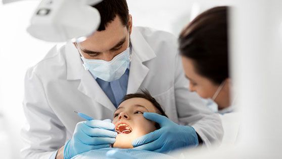Un dentista está examinando los dientes de un niño en un consultorio dental.