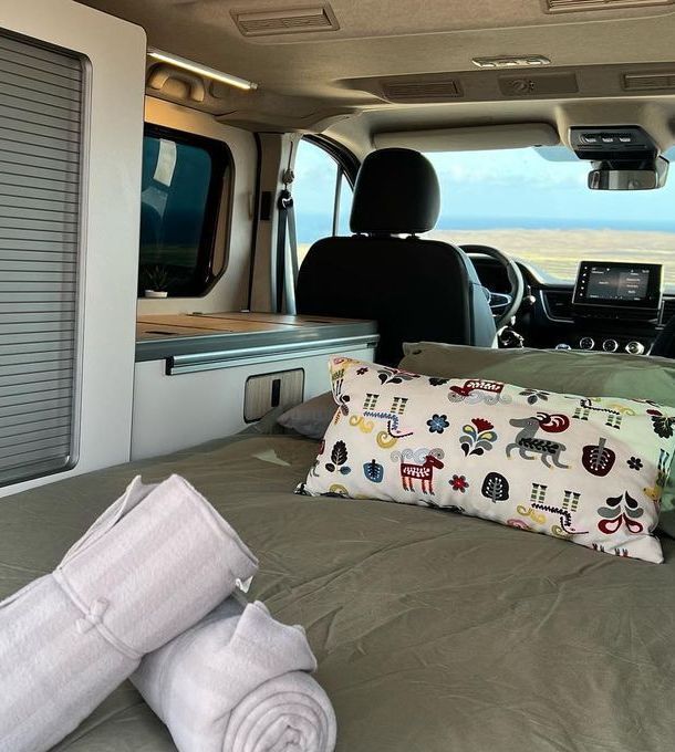 Una cama en la parte trasera de una camioneta con mantas y almohadas.