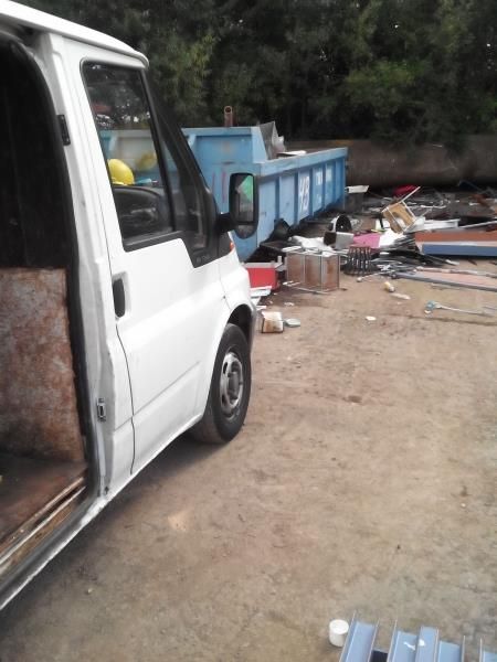 Ein weißer Lieferwagen steht neben einem blauen Müllcontainer