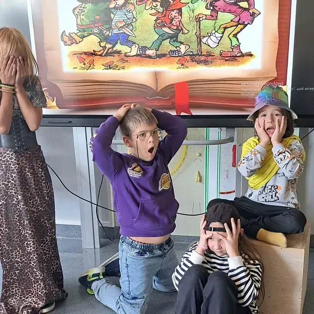 Kinder reagieren mit überraschten Gesichtsausdrücken vor einer Buchillustration.