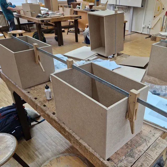 Zwei auf einer Werkbank zusammengeklemmte Holzkisten; Holzwerkstatt.