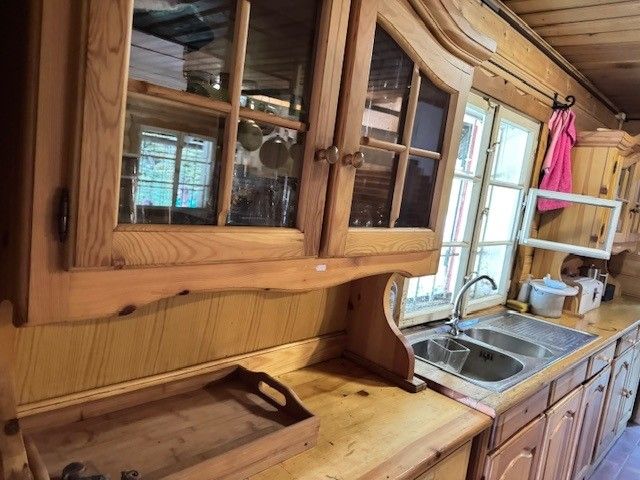 Küchenschränke und Spüle aus Holz in rustikalem Ambiente, mit Fenster und einem Holztablett.