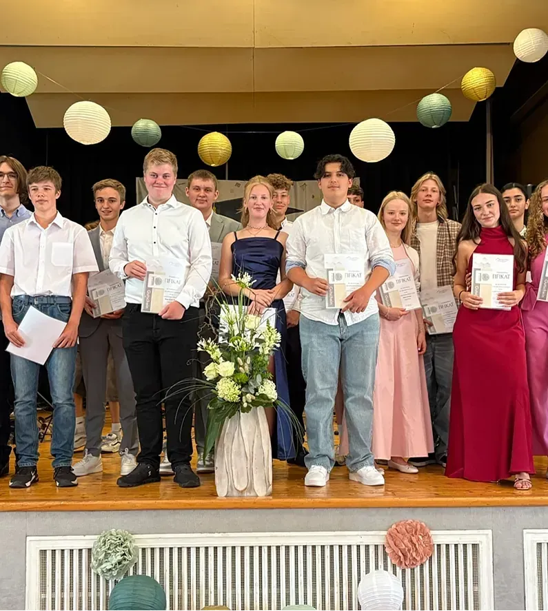 Eine Gruppe von Menschen feiert auf der Bühne. Einige halten Urkunden, die mit Papierlaternen verziert sind.