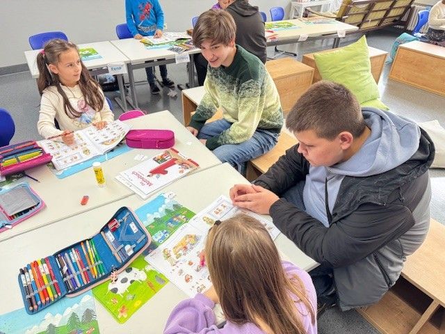 Kinder sitzen an ihren Schreibtischen, malen und arbeiten an Projekten in einem Klassenzimmer.
