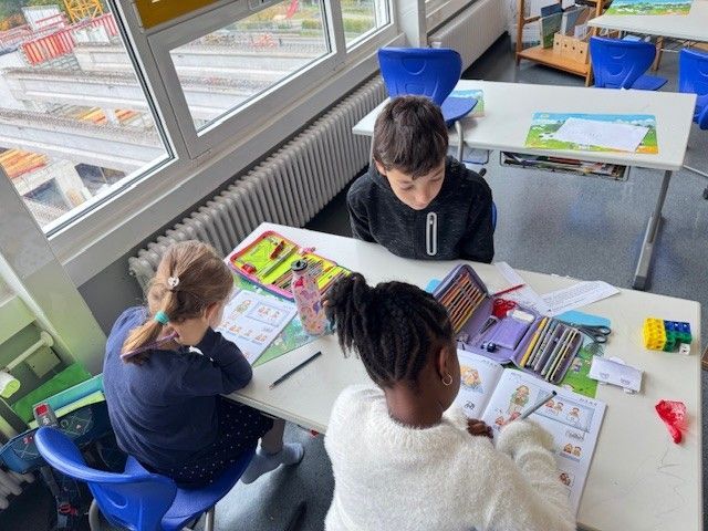 Kinder lernen an einem Schreibtisch in einem Klassenzimmer.