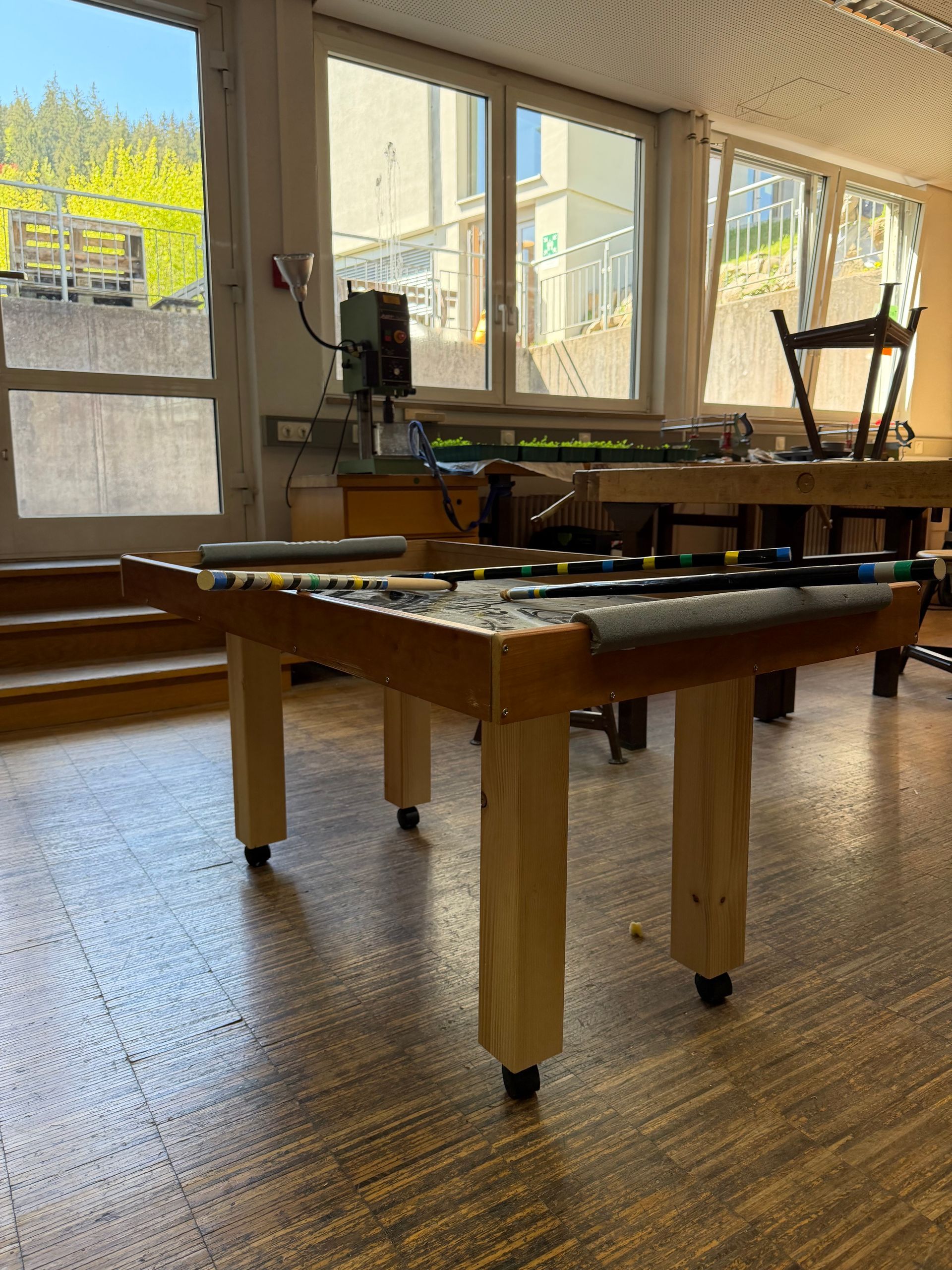 Game room with a foosball table and pool table near large windows in a bright sunroom.