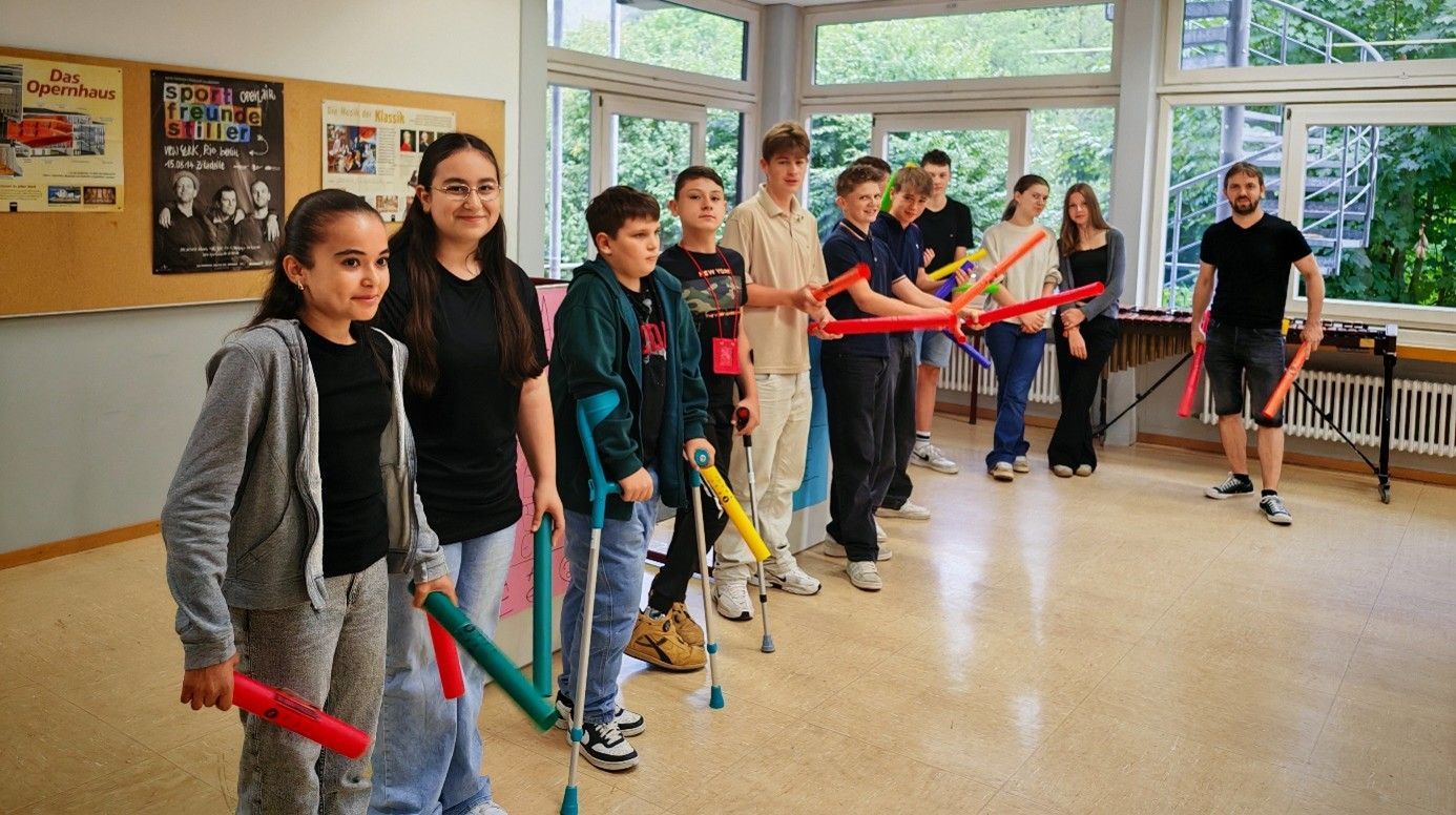 Schüler mit Schlaginstrumenten, Lehrer, Klassenzimmer, lächelnd.