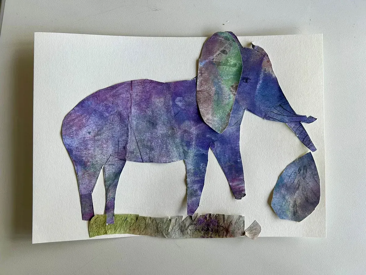 Collage aus violettem und blauem Papier, die einen Elefanten zeigt, der auf grünem Gras steht, neben ihm ein Stein.