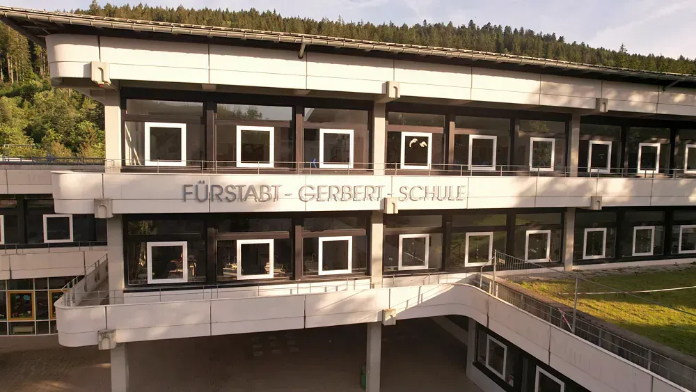 Schulgebäude mit großen Fenstern und einem Schild mit der Aufschrift