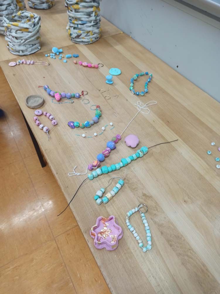 Tisch mit verschiedenen farbenfrohen Perlenarmbändern und Kunsthandwerksartikeln.