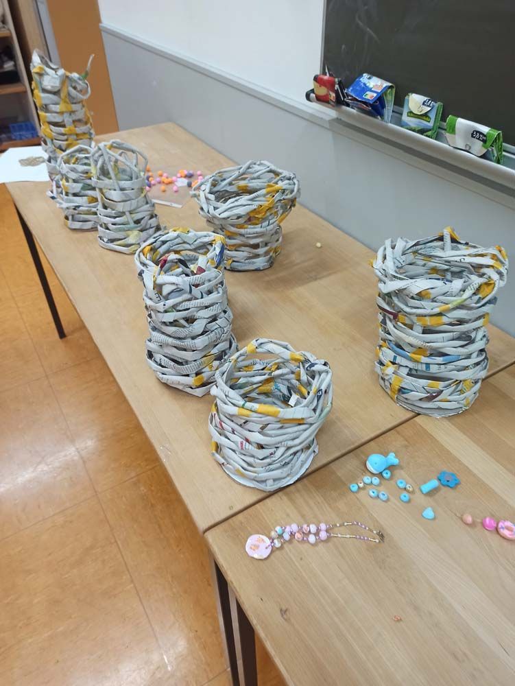 Mehrere in Papier eingewickelte Körbe auf einem Holztisch, möglicherweise ein Bastelprojekt.